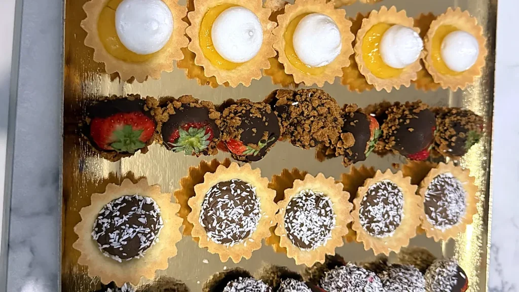 Plateau de mignardises : éclairs, tartelettes et fraises au chocolat pour baptême